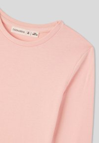 Jasnoróżowa koszula z długim rękawem, wykonana z miękkiej bawełny. Posiada klasyczny okrągły dekolt oraz metkę z rozmiarem 4/5, wzrost 104/110.