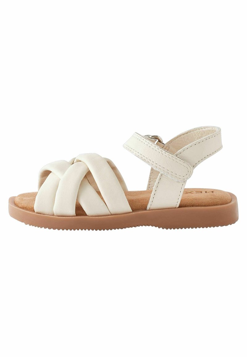 Sandali bianchi in pelle con cinturini incrociati e una cinghia alla caviglia sul retro. Soletta morbida marrone e suola in gomma testurizzata per una buona aderenza.