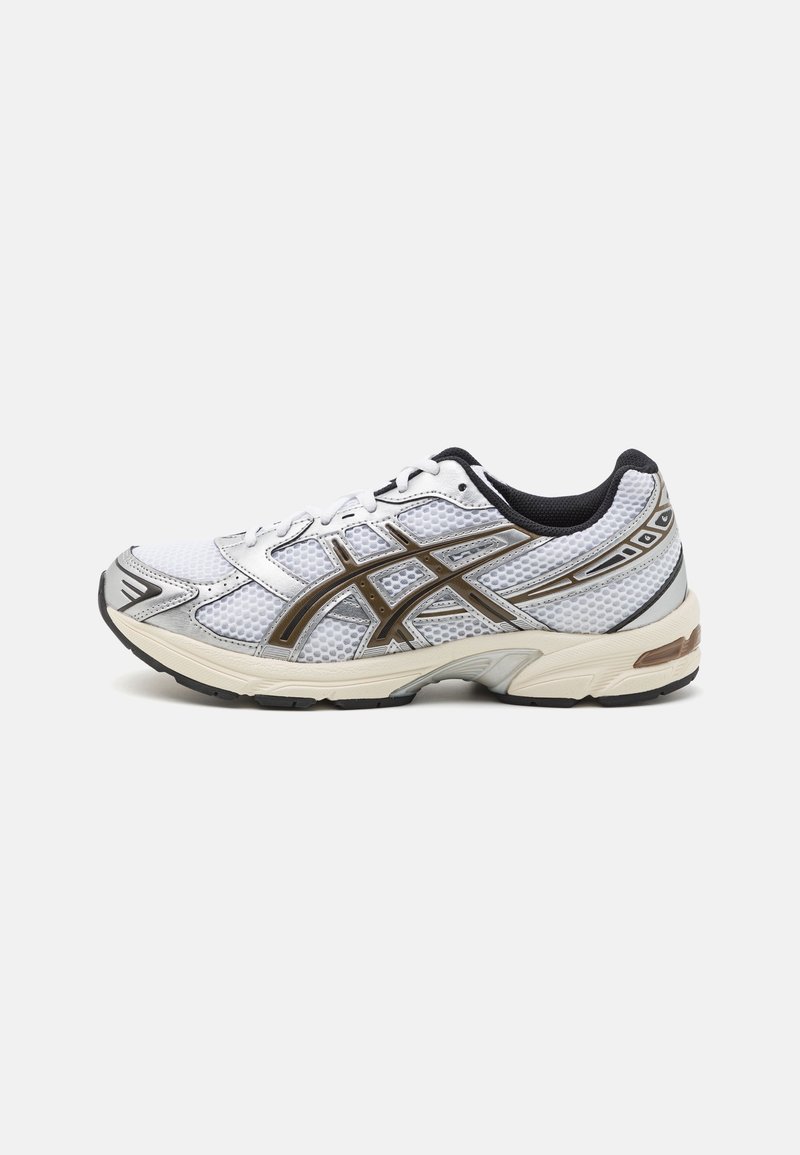 Chaussure de running blanche et noire avec tissu en mesh, semelle beige, doublure intérieure noire et bandes latérales marron foncé sur fond uni.