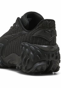 Czarny but sportowy z siateczkową cholewką z teksturowanymi akcentami, wyściełanym kołnierzem i profilowaną gumową podeszwą o różnych wzorach bieżnika.