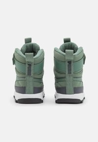 Sneaker alte verdi con upper texturizzato, collari imbottiti e una suola intermedia grigia scura a contrasto, dotate di un tassello posteriore per indossarle facilmente.