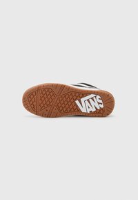 Vans'i spordijalatsi välistald, millel on pruun kummibaas tekstuurse haarde mustriga ja valge logo silmapaistvalt esindatud.