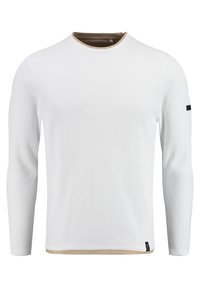 T-shirt à manches longues blanc avec une texture côtelée, un col rond et un col intérieur en contraste brun. Présente un logo noir sur la manche.