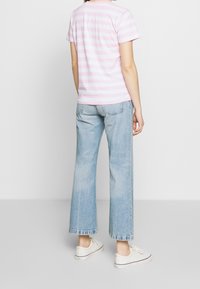 camiseta de algodón a rayas rosa y blanca, combinada con jeans de pierna ancha en azul claro. Zapatillas blancas informales completan el conjunto.