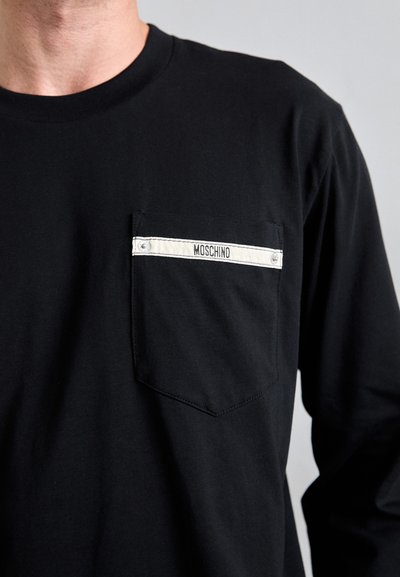 Svart langermet skjorte med brystlomme og en hvit stripe merket "MOSCHINO." Laget av mykt materiale med vanlig passform og enkel design.