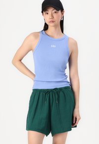 Ljusblå ribbad tanktop med "GAP"-logotyp; matchad med mörkgröna shorts med dragsko i texturerad tyg.