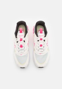 Tenisky Nike s bílým síťovaným a syntetickým svrškem, růžovými akcenty, černým límcem a průhlednou podrážkou s texturovanými vzory.