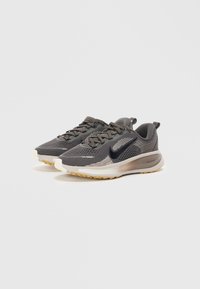 Scarpe sportive grigie con dettagli neri, tomaia in mesh, design testurizzato, ammortizzazione React e suola in gomma per trazione.