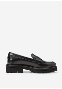 Mocasines de piel negra con suela de goma gruesa y costura de mocasín, perfil lateral sobre fondo blanco.
