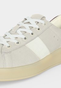 Baskets en daim beige clair avec des lacets blancs, une bande blanche sur le côté et une semelle beige.