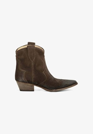 Bottine western en daim marron foncé à bout pointu, talon en bois empilé bas, et languettes au col, visible de profil sur fond blanc.