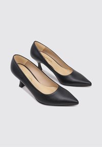 Zapatos de tacón de cuero negro con punta puntiaguda, tacón bajo y acabado liso. Interior con forro beige y logo impreso en dorado.