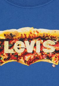 Μπλε βαμβακερό μπλουζάκι με γραφικό μιας φέτας πίτσας με το κείμενο "Levi's" σε έντονη γραμματοσειρά, που παρουσιάζει ζωντανά χρώματα και υφές.