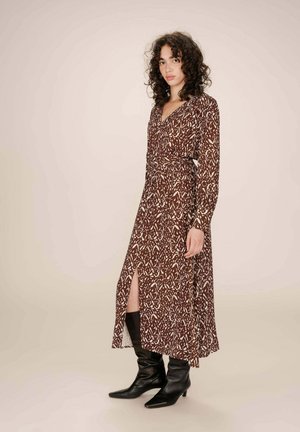 Robe midi à motifs marron avec des manches longues, un décolleté en V et une fente sur le côté ; associée à des bottes noires à bout pointu pour le contraste.