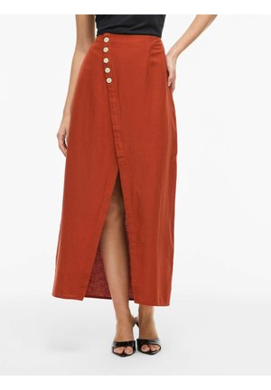 Magas derekú, égett narancssárga maxi szoknya elülső hasítékkal, az oldalon öt bézs gombbal, fekete nyitott orrú magassarkúval viselve.