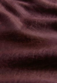Blødt, rynket brunt stof med subtil tekstur og hængende folder, der skaber blide skygger.