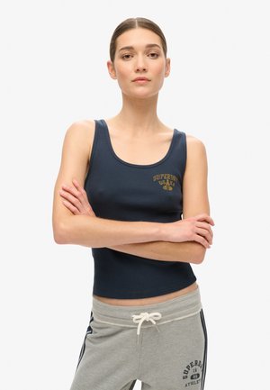 Granatowy, prążkowany top na ramiączkach z dekoltem w serek i złotym logo z przodu. Połączony z jasnoszarymi spodniami dresowymi z ciemnymi paskami i logo.