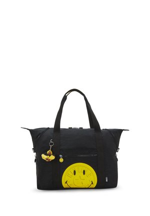 Schwarze Duffeltasche mit gelbem Smiley-Aufnäher und kleinem Plüschaffen-Schlüsselanhänger, der an einem Griff hängt.