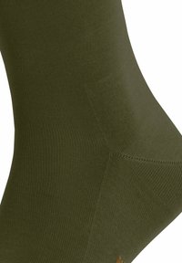 Calzino verde oliva realizzato in tessuto a coste, con punta senza cuciture e tallone rinforzato, che mette in evidenza una texture morbida e una vestibilità aderente.