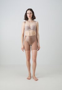 Conjunto de sujetador y pantalones cortos de tiro alto en tela color topo claro. El sujetador presenta copas suaves con tirantes finos; los pantalones cortos tienen una textura semitransparente.