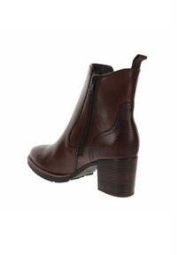 Bottine en cuir brun avec une fermeture éclair sur le côté, un talon texturé et une pointe arrondie, présentant une surface lisse et des accents détaillés contrastants.