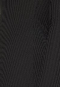 Svart ribbat tyg med vertikala linjer och en jämn textur. Materialet verkar elastiskt och har en sömlös design.