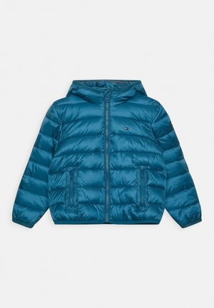 Niebieska kurtka puchowa z kapturem, z przednim zamkiem błyskawicznym, dwoma zapinanymi na zamek kieszeniami i małym logo na klatce piersiowej, ułożona na białym tle.