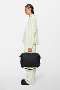 Borsa per laptop rettangolare nera con superficie texturizzata, doppie cerniere e tracolla regolabile, tenuta da una persona con abbigliamento chiaro.