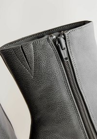 Grå læder ankelstøvler med en tekstureret overflade, der har en lynlås fortil og minimal syning. Fås i et stilrent design.