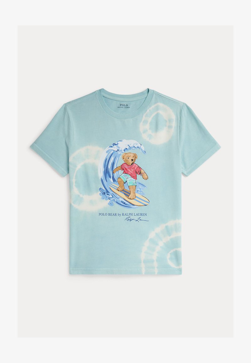 Φανελάκι βαμβακερό tie-dye σε ανοιχτό μπλε χρώμα με έναν αρκούδο που κάνει σερφ σε κύμα, φοράει κόκκινο μπλουζάκι και aqua σορτς, με το κείμενο "Polo Bear by Ralph Lauren" από κάτω.