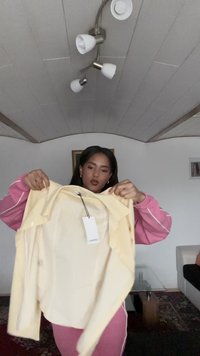 Yellow striped button-up shirt held up, with a tag visible; made from lightweight fabric, featuring a collared neck and short sleeves.