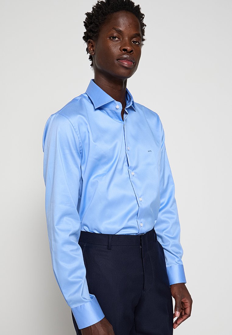 Helles blaues Langarmhemd mit spitzem Kragen und Knopfleiste. Aus glattem Stoff gefertigt, verfügt es über ein kleines gesticktes Logo auf der Brust.