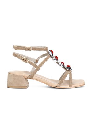 I sandali con tacco beige in suede presentano un tacco a blocco, molteplici cinturini e un accento di gioielli rossi nella parte anteriore. Soletta in pelle liscia.