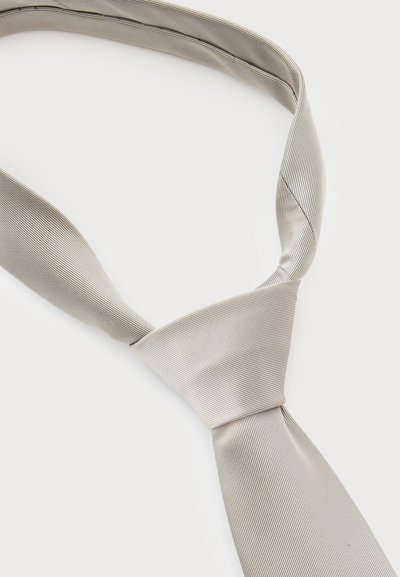Cravate gris clair avec un motif subtil à rayures diagonales, nouée en nœud classique et posée à plat sur un fond blanc.