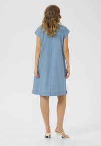 Robe en denim bleu à manches courtes, coupe droite, longueur genou, détails de couture subtils et coupe décontractée.