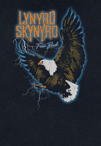 Czarna koszulka z wizerunkiem orła z rozpostartymi skrzydłami, obrysowanego na niebiesko, z pomarańczowym napisem "LYNYRD SKYNYRD" oraz "Free Bird" poniżej.