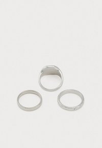 Conjunto de três anéis de prata: um em forma de cúpula lisa, um fino e outro com um padrão torcido, todos exibindo um acabamento metálico brilhante.