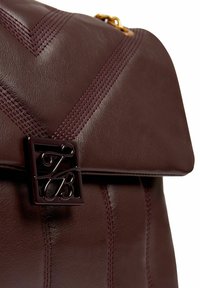 Borsa in pelle color marrone scuro con cuciture diagonali, forma strutturata e chiusura quadrata in metallo con dettagli intricati.