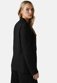 Svart linneblazer med en strukturerad design, slagkrage och texturerad tyg. Har lång ärm och rak nederkant för en skräddarsydd passform.