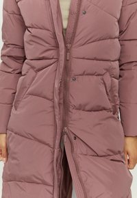 Helle lila Pufferjacke mit Reißverschlussfront, Druckknöpfen und seitlichen Taschen. Verfügt über gestepptes Design und eine glatte, weiche Textur.