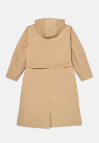Beige plašč do gležnjev z kapuco, dolgimi rokavi, pasom in zračnim odprtjem na hrbtu. Narejen iz gladkega blaga z minimalističnim dizajnom.