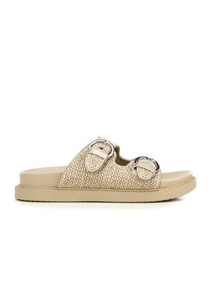 Sandalia deslizable de tejido beige con dos hebillas plateadas ajustables y suela plana de goma, vista lateral sobre fondo blanco.