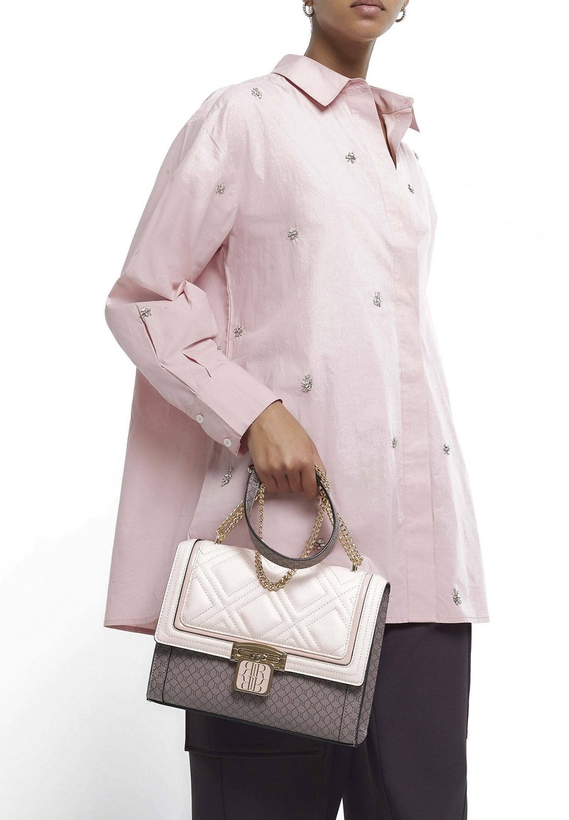 Roze katoenen shirt met geborduurde accenten, gecombineerd met een twee-kleurige gewatteerde handtas met kettinghandvatten en een metalen sluiting.