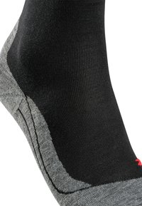 Calcetín negro y gris con textura acanalada, con talón y puntera reforzados. Presenta un acento rojo cerca de la puntera y detalles de costura en contraste.