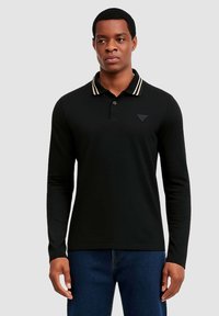Czarna koszulka polo z długim rękawem i kołnierzykiem ozdobionym kremowymi paskami. Charakterystycznym elementem jest małe logo marki na piersi. Gładka struktura.