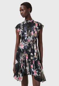 Blumenkleid mit kurzen Ärmeln, das einen schwarzen Hintergrund, lebendige rosa und grüne Blumenmuster sowie ein tailliertes Oberteil mit schwingendem Rock aufweist.