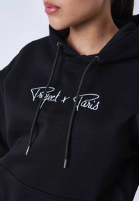 Zwarte hoodie van een katoenmix, met een voorzak, trekkoorden met metalen aglets en witte geborduurde logo-tekst.