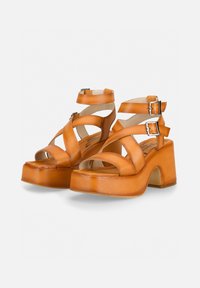 Brown leather platform sandals with multiple crossed straps, side buckles, and a thick block heel. Open toe design with a smooth texture.
