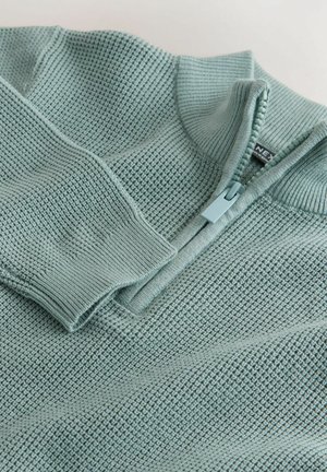 Gaiši zila adīta džempera ar pusrāvēja apkakli, ribotām aprocēm un teksturētu audumu ar smalku režģa rakstu.