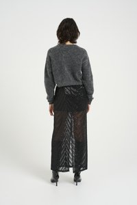 Gray knit sweater paired with a sheer black sequined skirt featuring chevron patterns. The ensemble is complemented by black heeled boots.